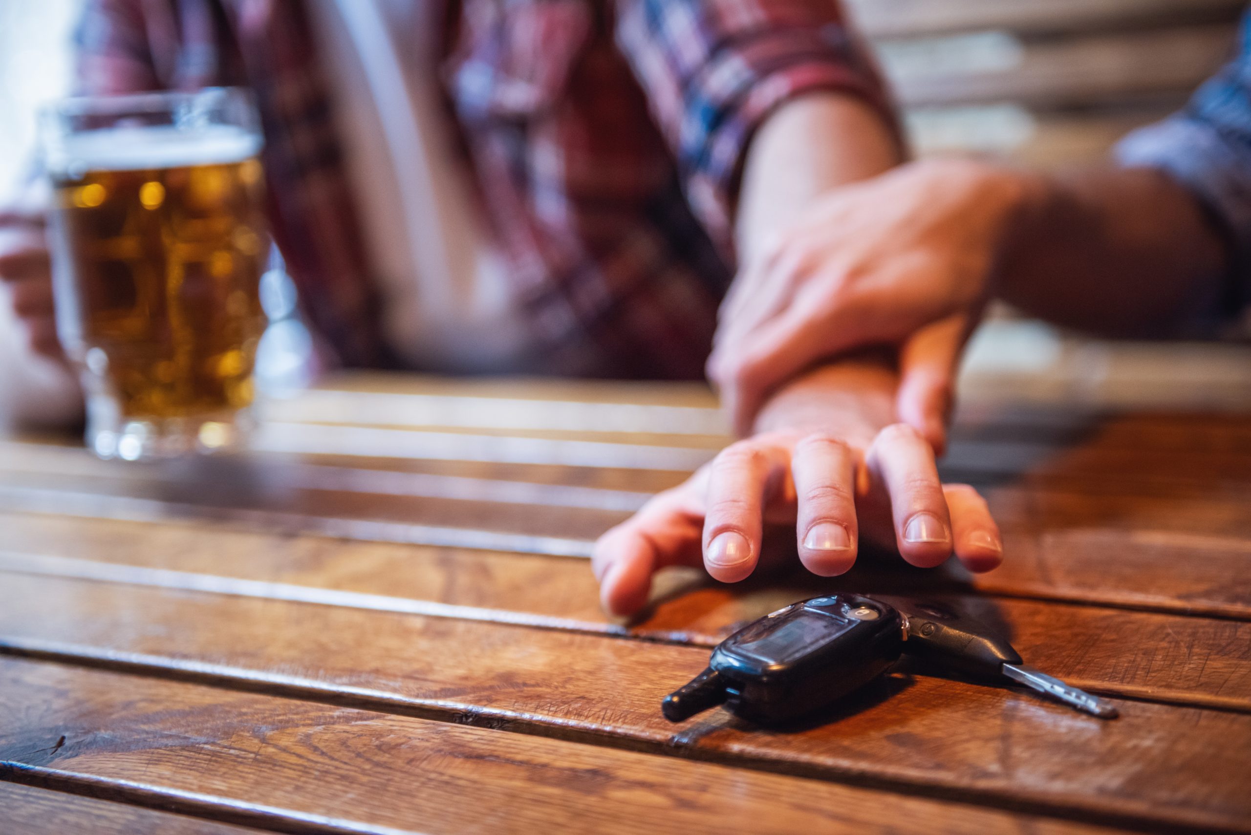 image of a drunk man reaching for his car keys and someone stopping him