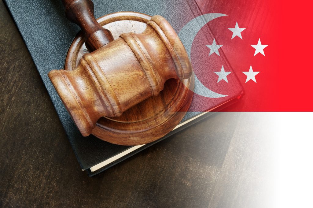 legal book, gavel, and singapore flag indicating the laws in the country