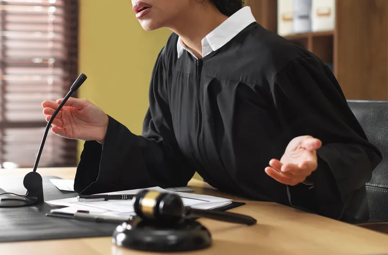 a female judge at a pre-trial court talking to the accused and his lawyer for theft in Singapore