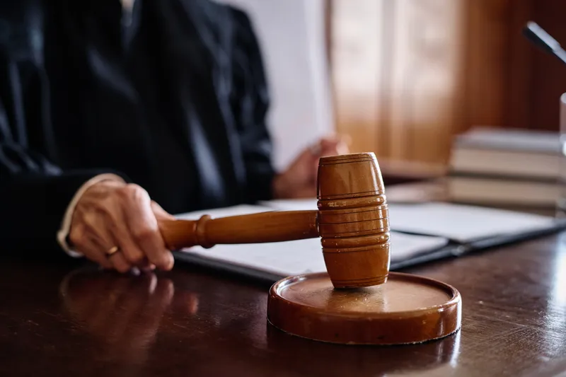 a courtroom judge hitting a sounding block with a wooden gavel