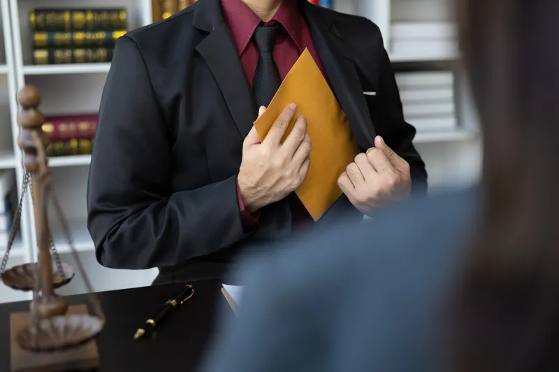 a criminal defence attorney putting a brown file envelope in his suit, indicating confidentiality of the case he handles