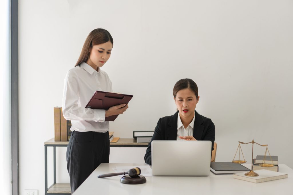 Legal professionals review case information on a laptop and tablet during a theft or misappropriation matter.
